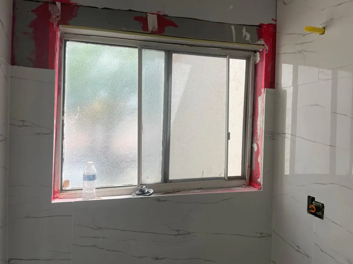 Marble wall tile around a window during a bathroom remodel by JC General Painting in South Florida