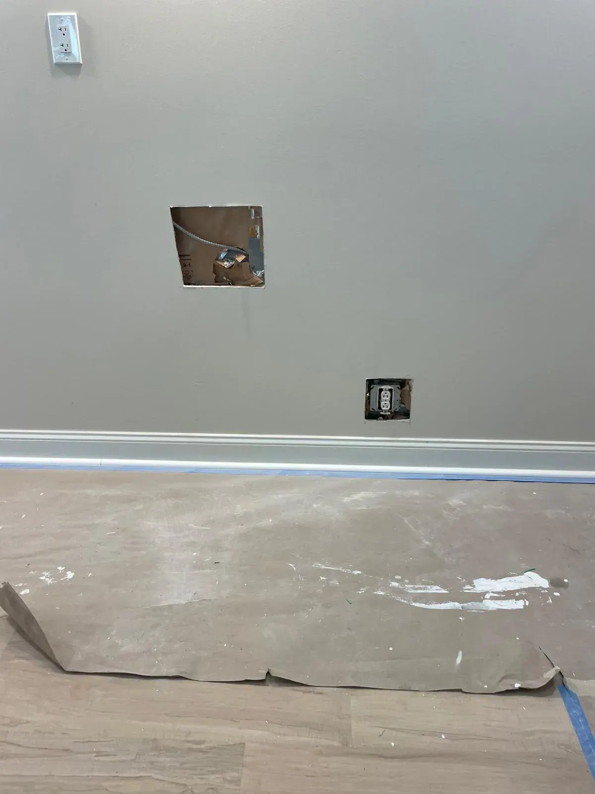 Drywall openings prepped for repair above a white baseboard by JC General Painting in South Florida