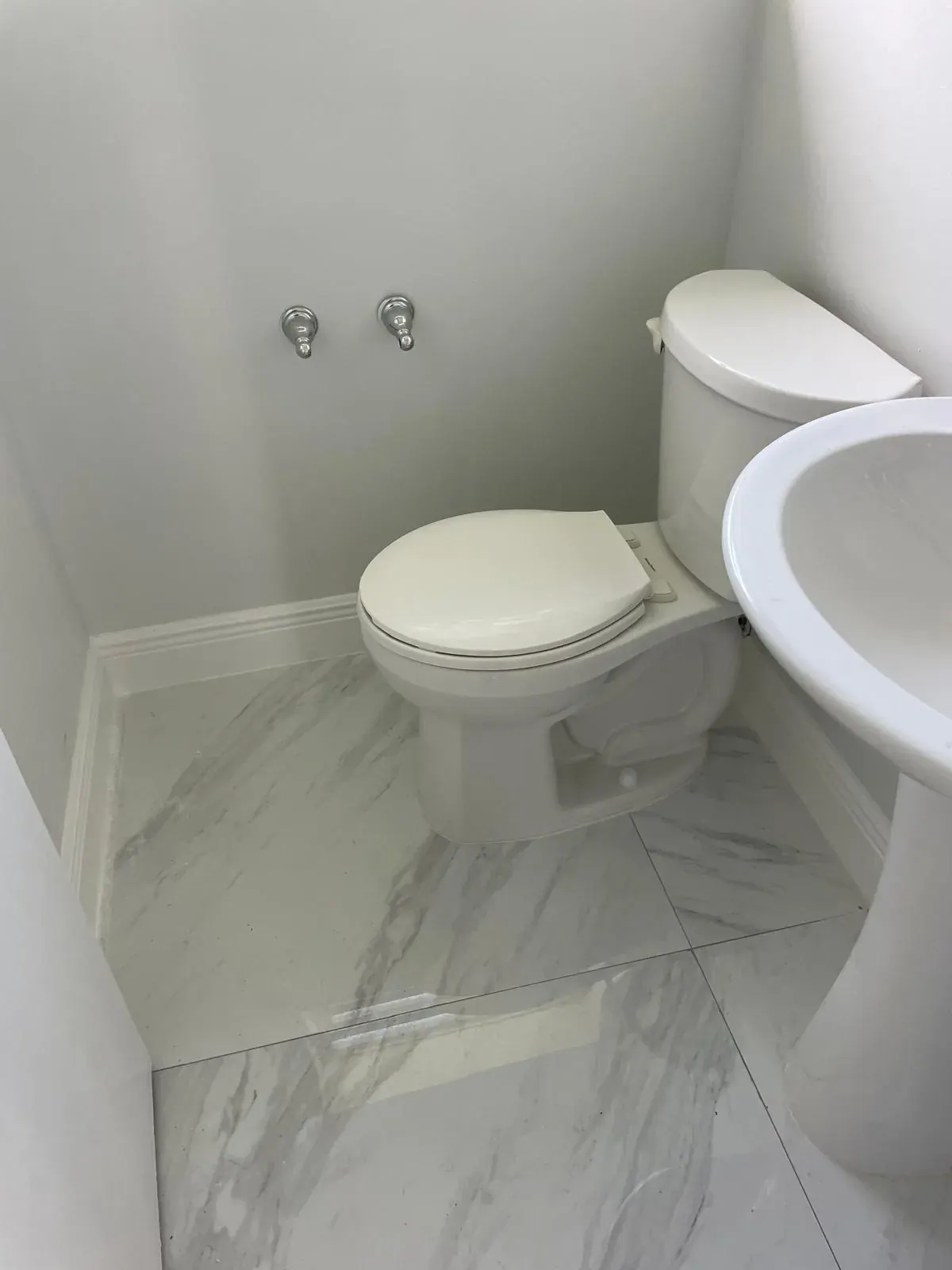 Half-bathroom remodel with marble tile floor and white baseboards by JC General Painting in South Florida