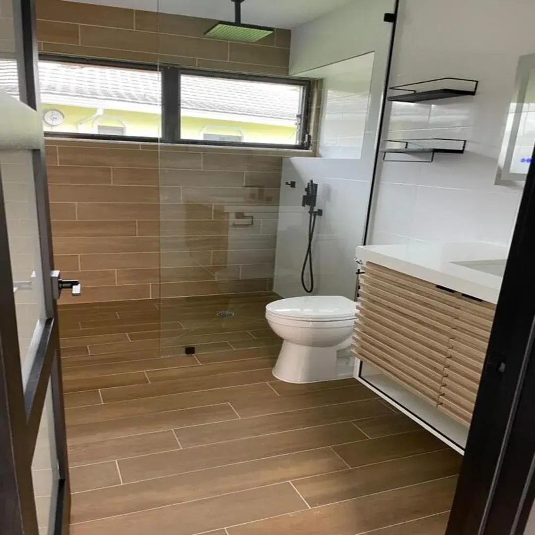 Wood-look tile bathroom with glass shower by JC General Painting in South Florida