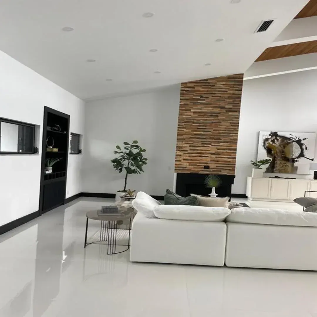 Modern living room with wood feature wall and fireplace by JC General Painting in South Florida