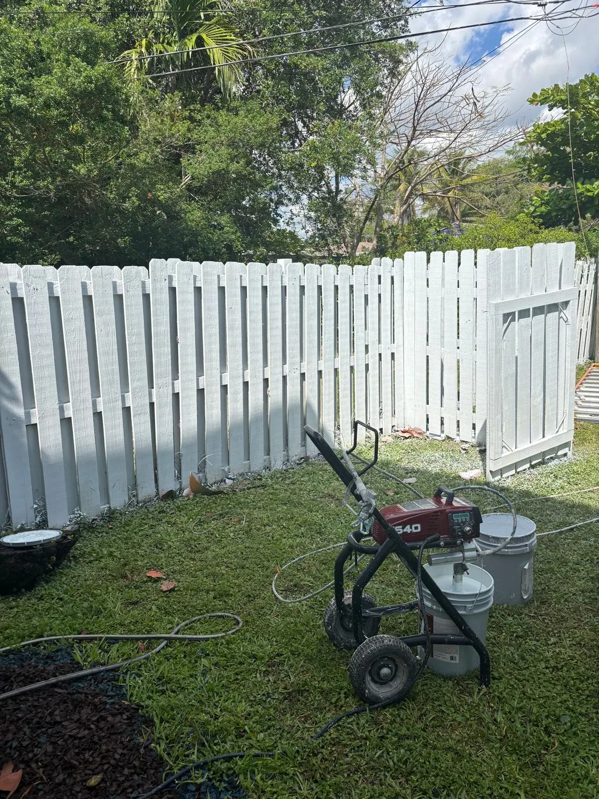 Freshly painted white wood privacy fence and gate by JC General Painting in South Florida