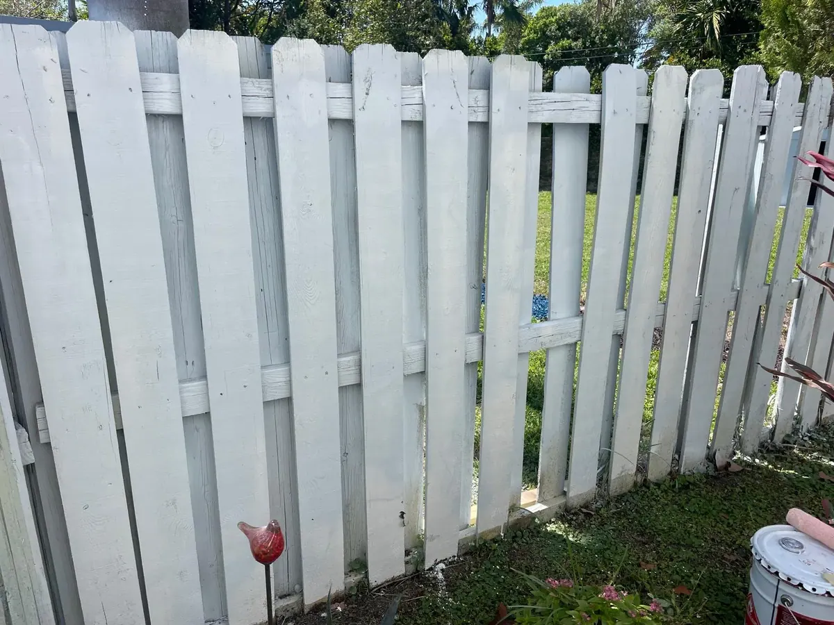 Repaired and repainted white wood picket fence by JC General Painting in South Florida